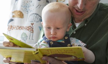 Dad and adopted baby reading on world book day