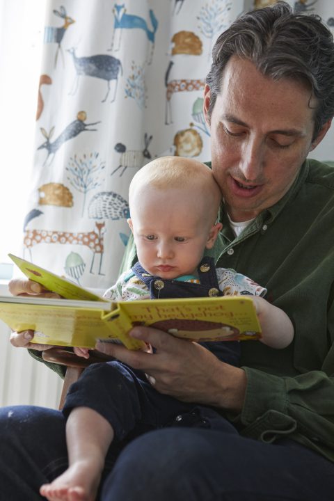 Dad and adopted baby reading on world book day