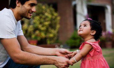 Asian adoptive Dad holding the hands of adopted asian daughter