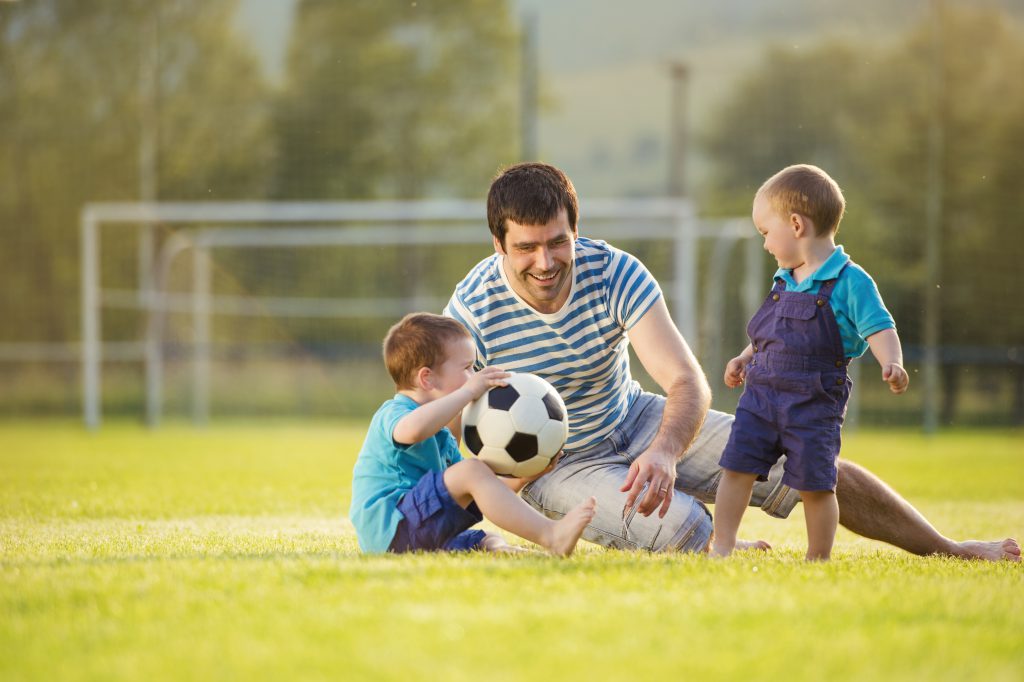 Adoptive father playing football with adopted sons