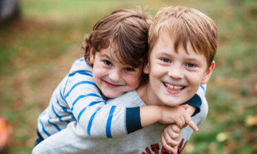 Adopted boy gives his younger brother a piggy-back