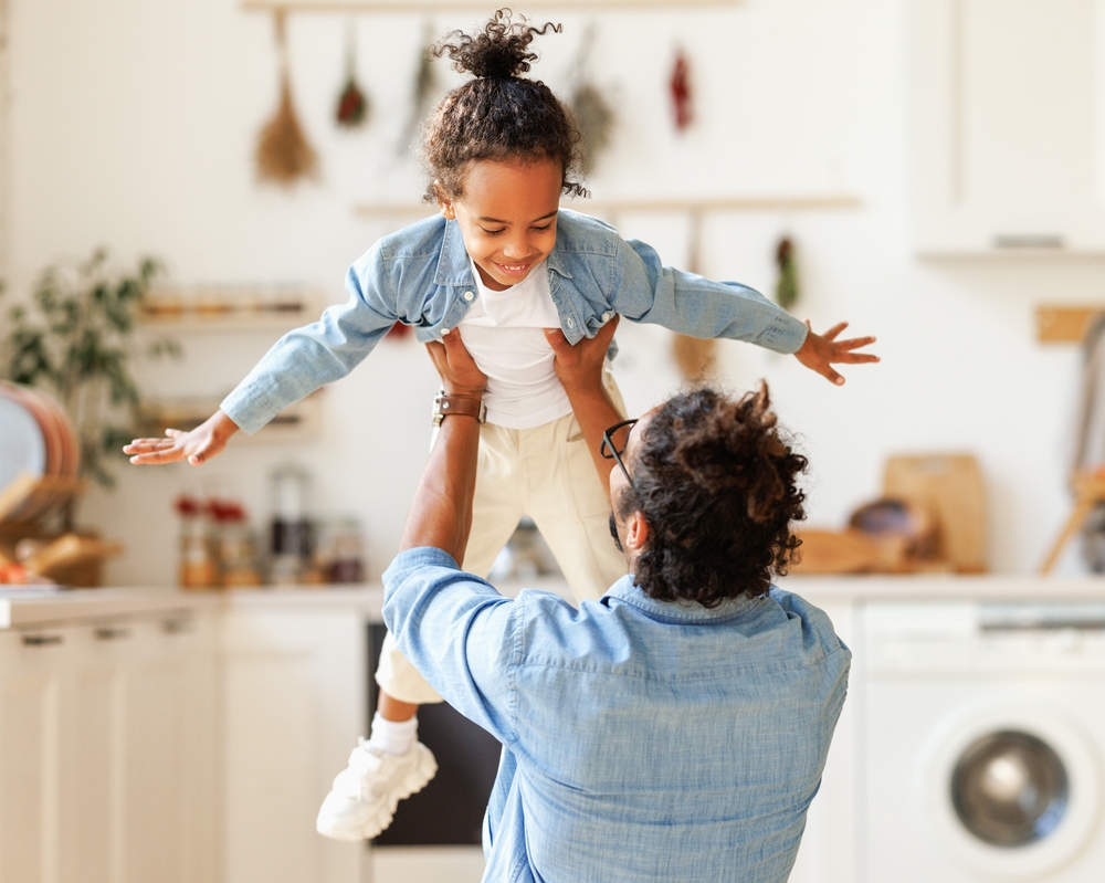 Black adoptive Dad spins black adopted son around in the air